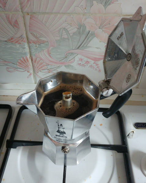 Opened Moka Pot on the hob with coffee in the top chamber